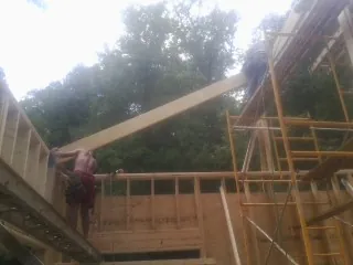 Carpenter raising a rafter beam on a new second story frame in Prairie View