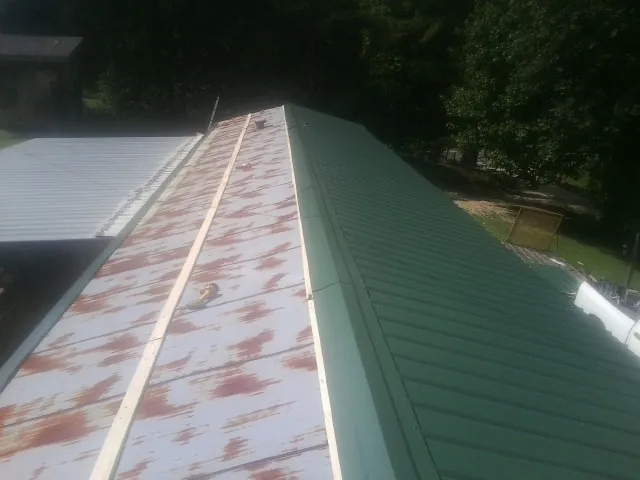 Old rusted panels beside newly installed green metal roofing — Wind Damage Roof Repair by Roofing Brothers in Prairie View