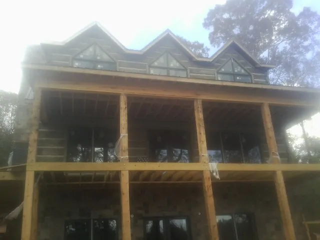 Dormers and porch framing on a large log home under construction — Roof Coating work by our crew in Prairie View