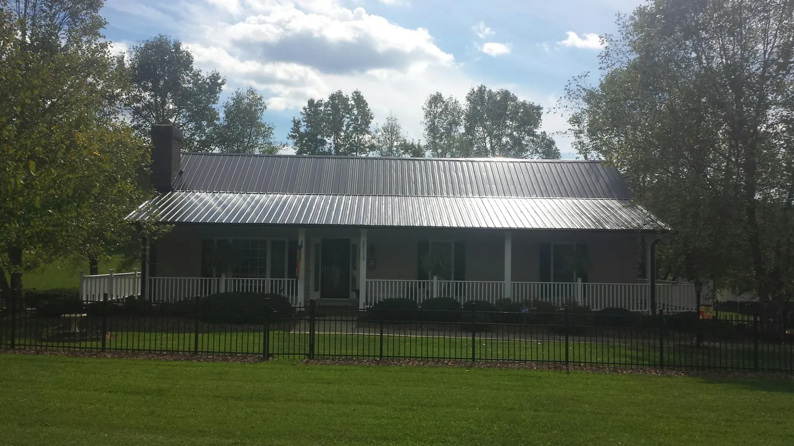 Gray metal roof on a brick ranch with a full width front porch — Gutter Guard Installation work by our crew in Prairie View