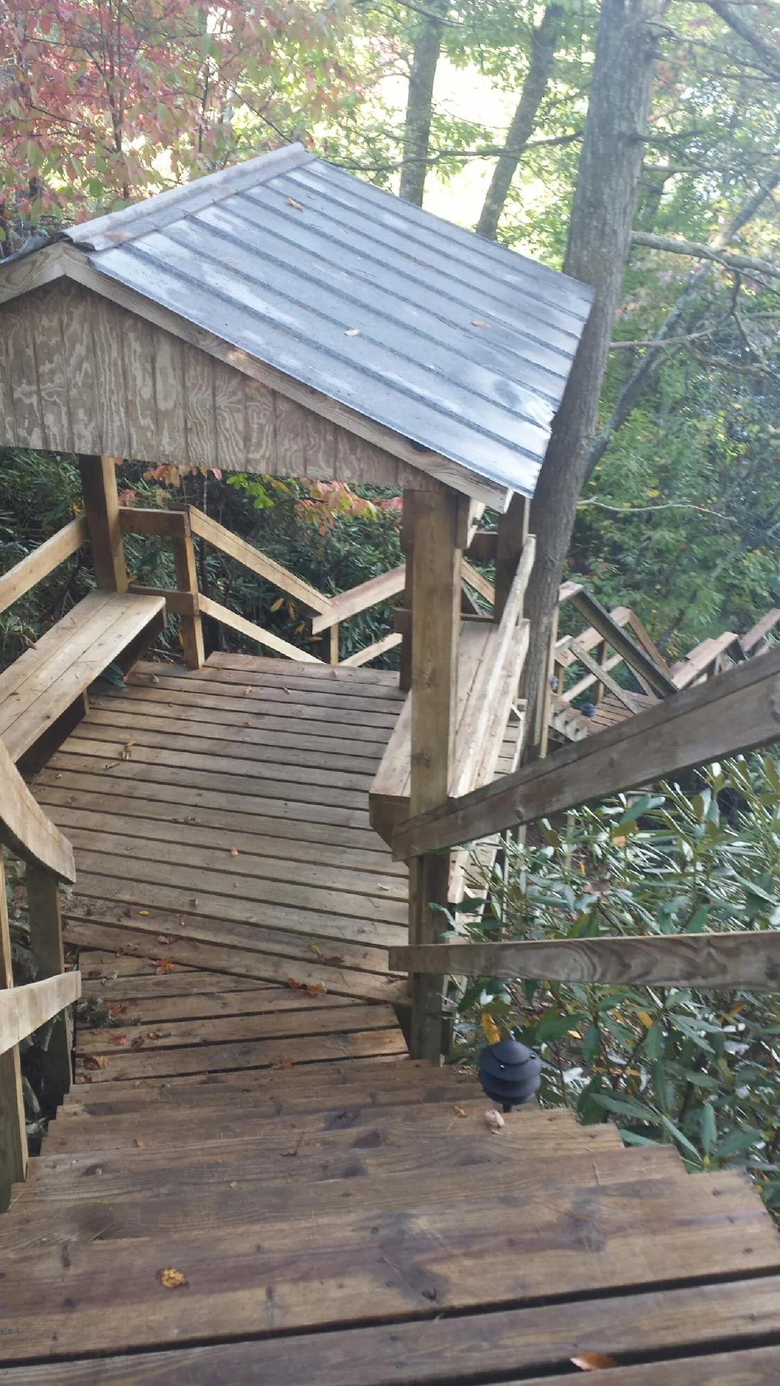Metal roofed shelter over wooden steps on a wooded walkway — Skylight Repair & Installation work by our crew in Prairie View
