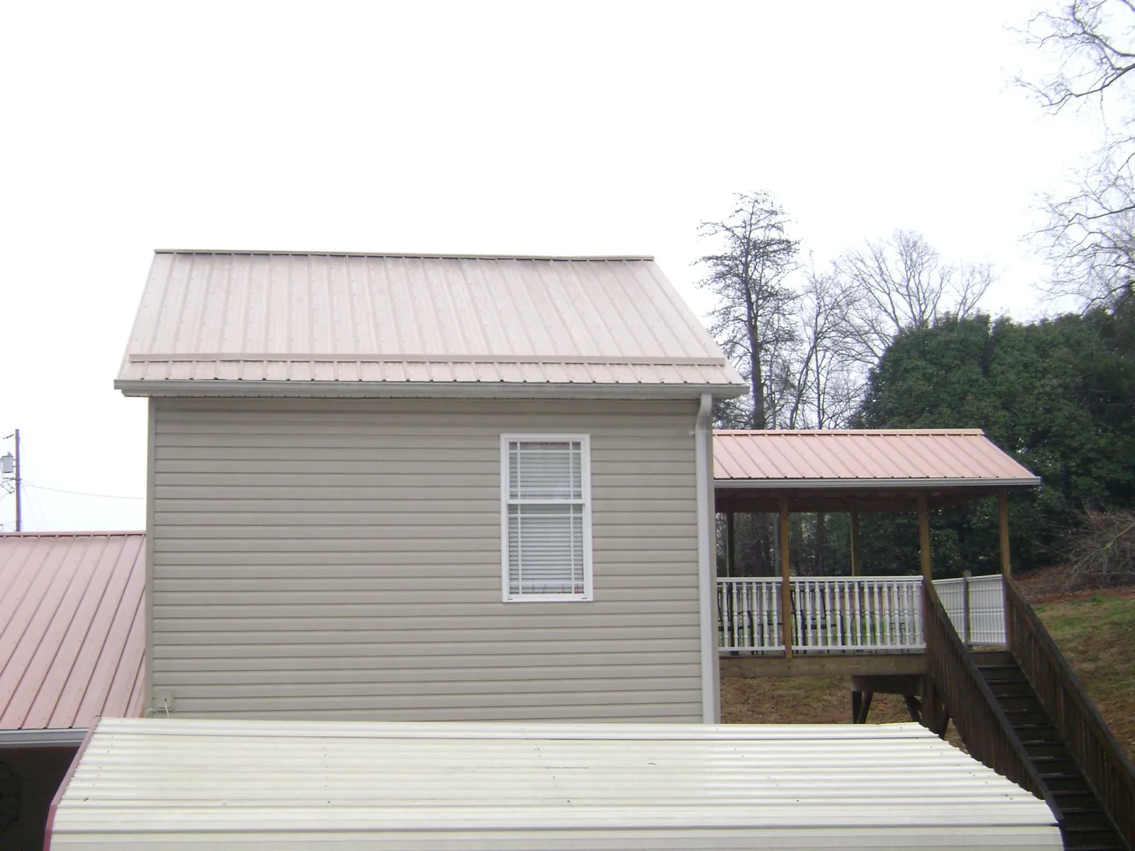 Tan metal roofs on a two story addition and attached porch, from a Roof Replacement job in Prairie View